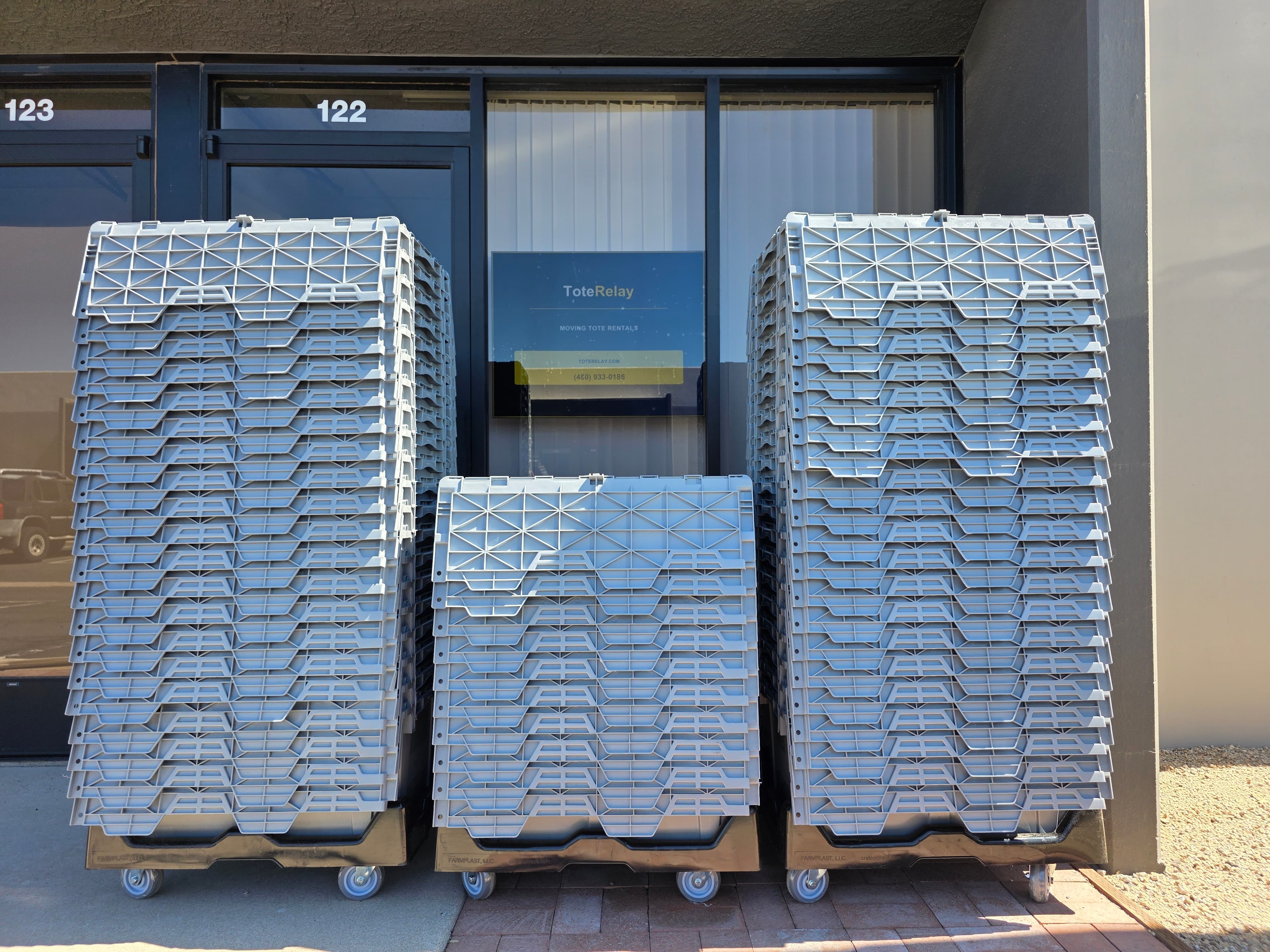 Moving totes and dollies outside the Tote Relay entrance, with suite 122 above the door